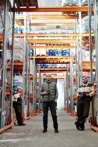 Warehouse manager standing beside pallets and truck
