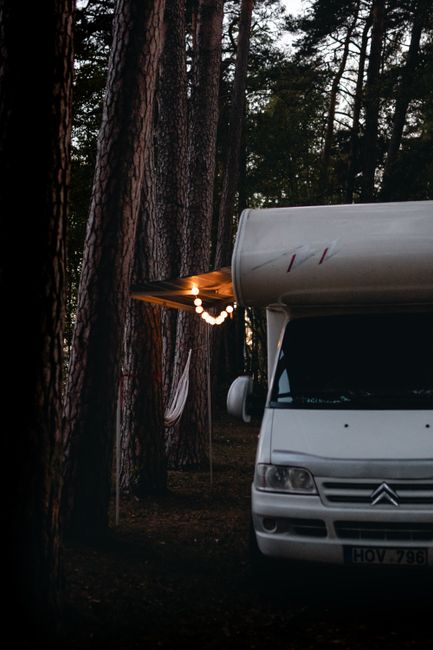 Parked rental RV at a quiet forest campground with mountains in the background