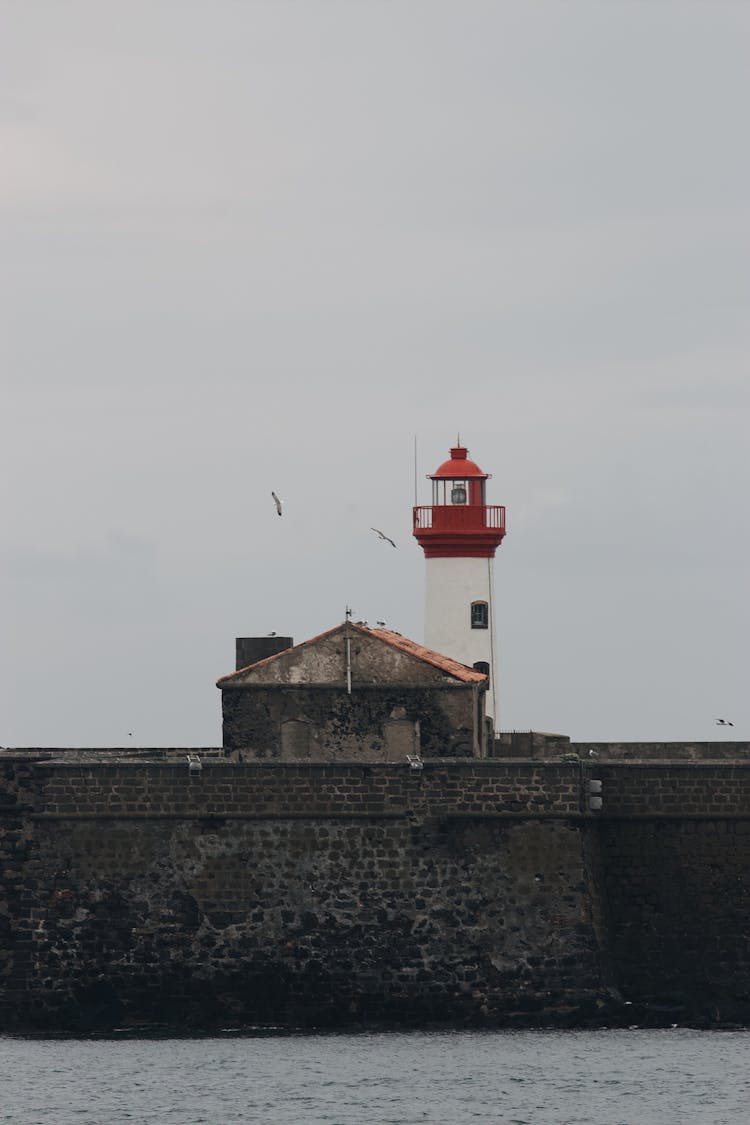 Beacon On Seashore Against Overcast Sky