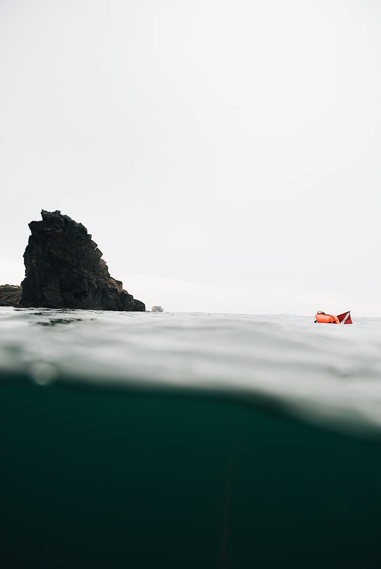 Steep Rock And Inflatable Boat Over Sea Surface