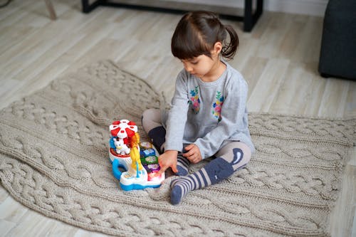 プラスチックのおもちゃで遊ぶ灰色のセーターの女の子