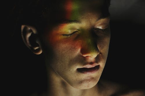 Free Freckled teenager with neon lights on face Stock Photo