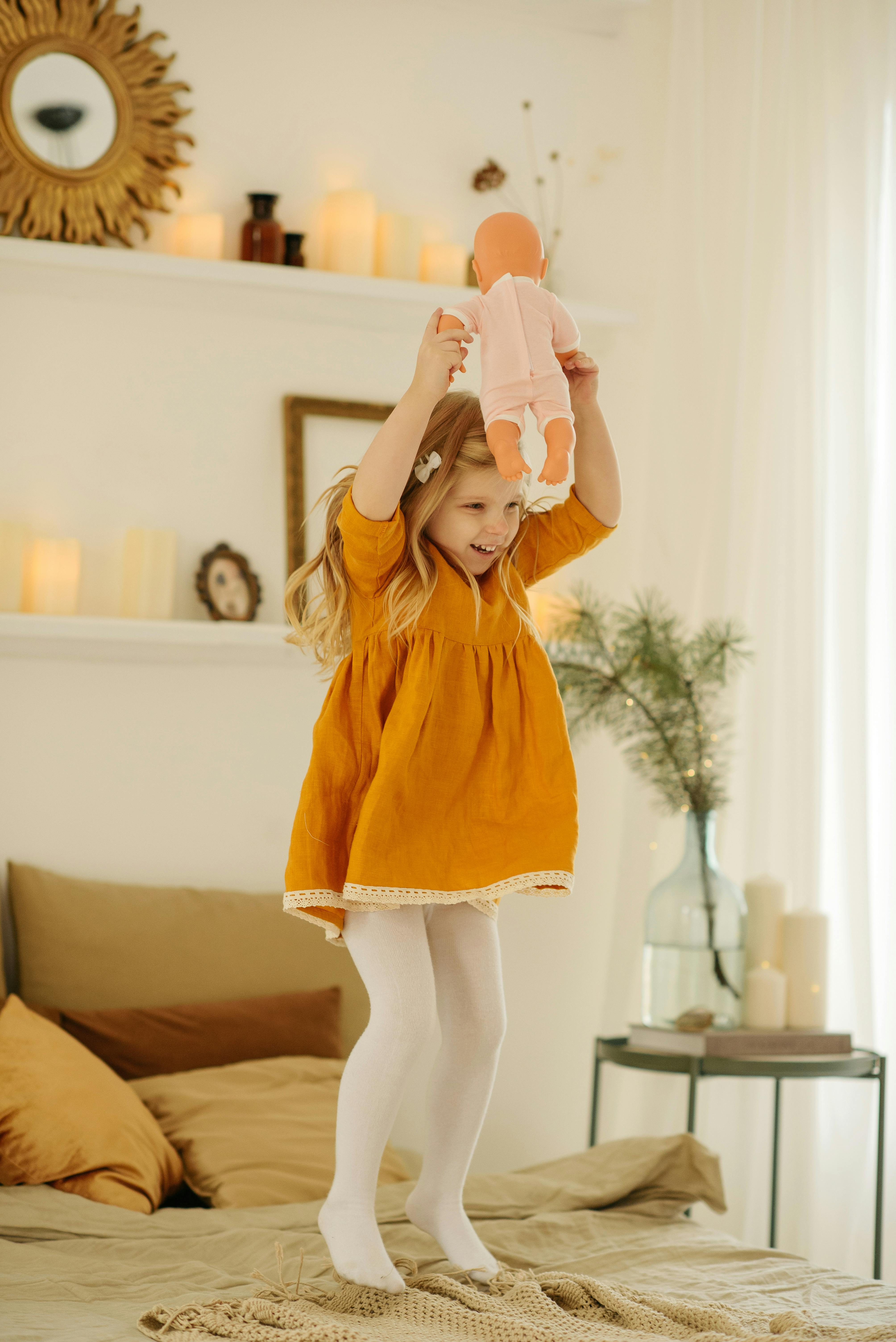 Girl in Orange Dress Holding Baby Doll · Free Stock Photo