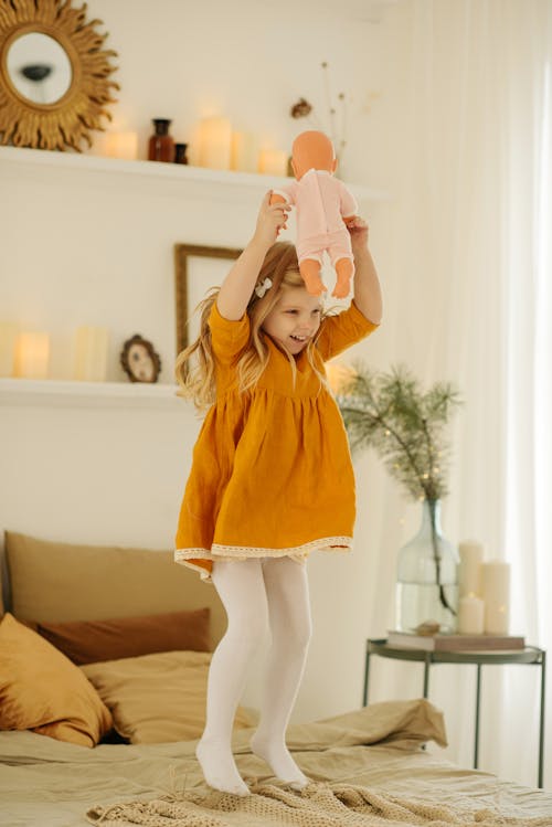 Girl in Orange Dress Holding Baby Doll
