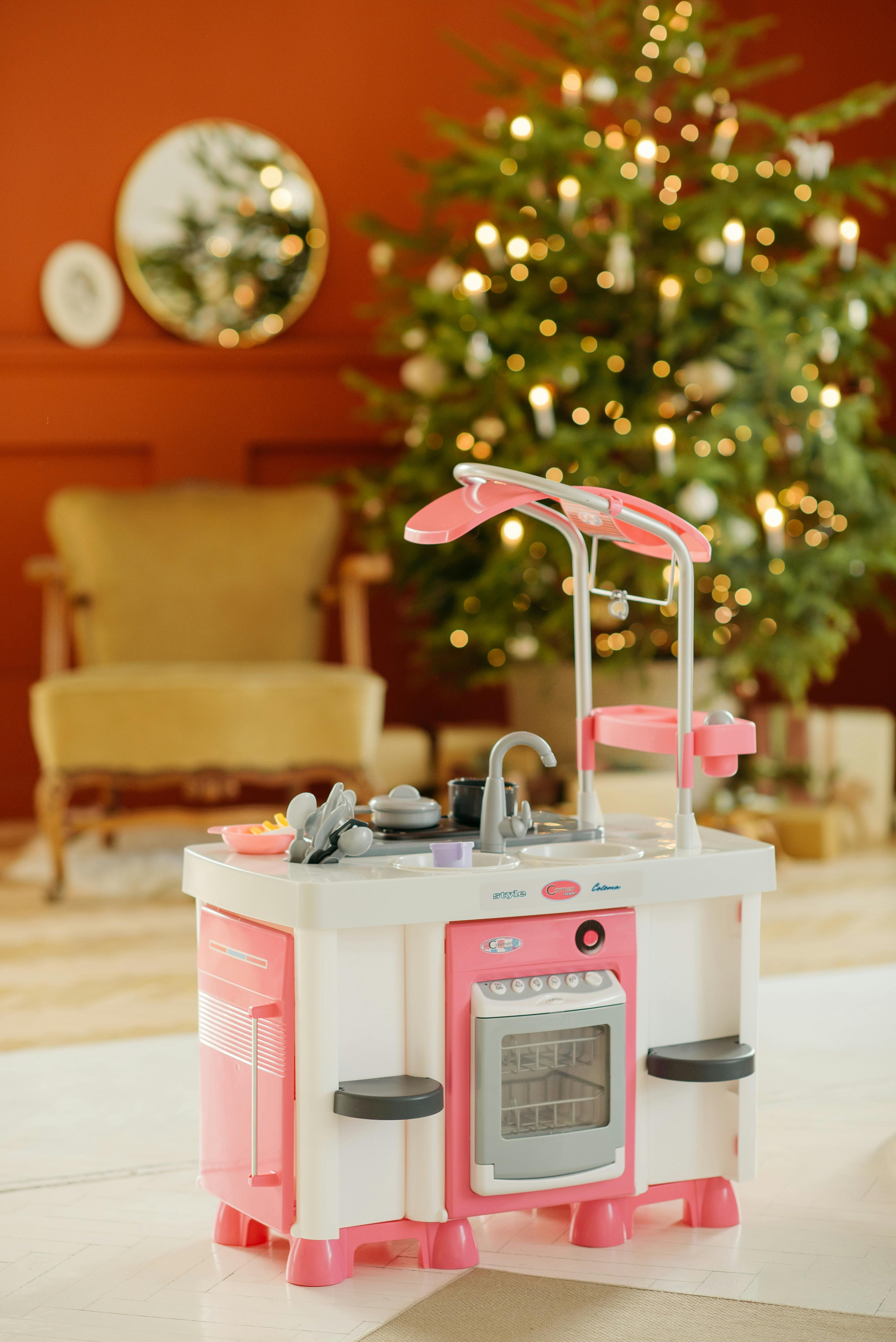 在带有圣诞树的节日房间里，有一套色彩鲜艳的儿童厨房玩具套装