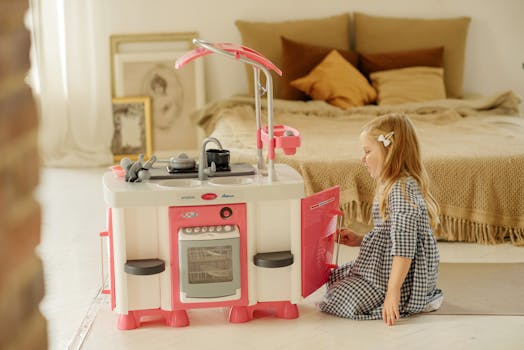 A young girl plays with a toy kitchen set in her bedroom, creating imaginative play moments.