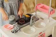 一个年轻女孩正在室内摆弄玩具厨房，富有想象力地玩耍，这非常适合表现童年和创造力的概念