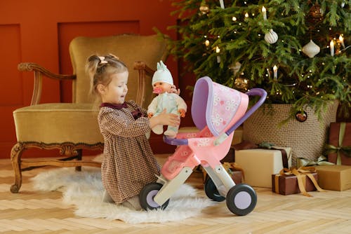 Free Girl in Plaid Dress Playing With Baby Doll Stock Photo