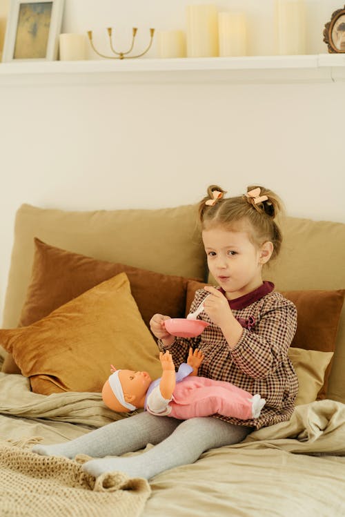 Girl in Plaid Dress Playing With Baby Doll