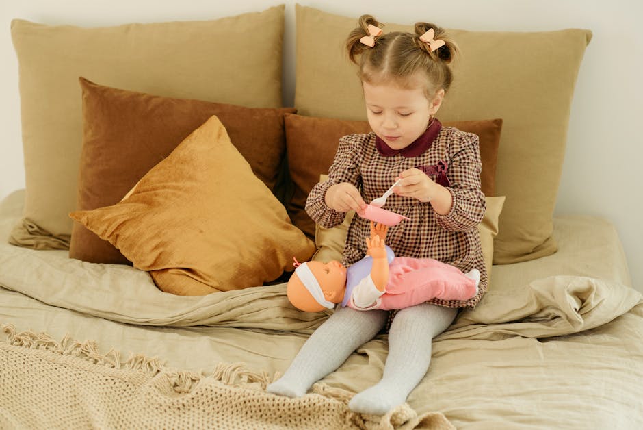 Cute little girl playing with a doll on a cozy bed indoors, fostering imaginative play.