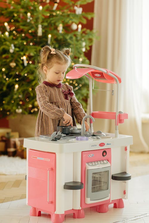 Free Girl in Plaid Dress Playing With Kitchen Toy Stock Photo