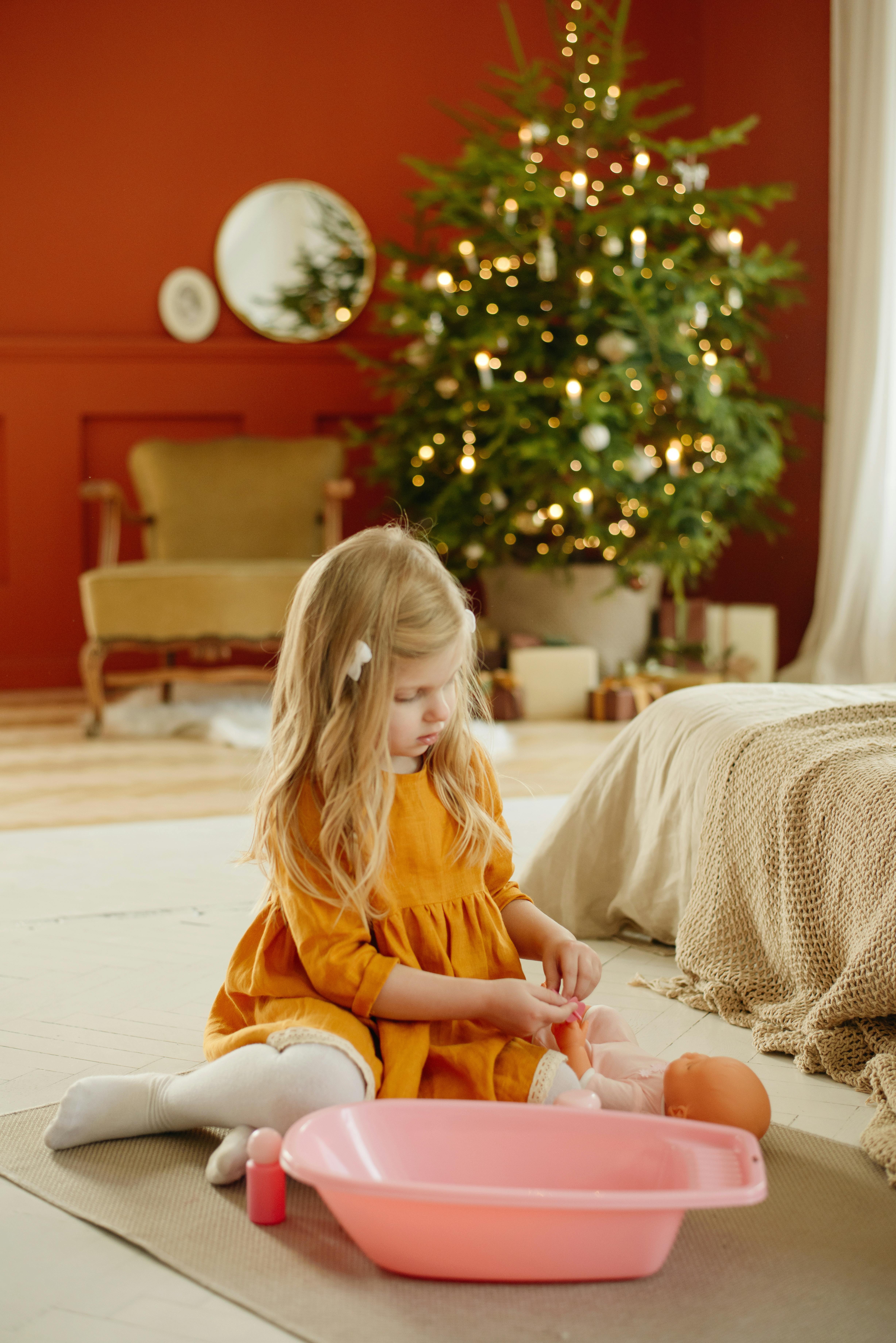 girl in orange dress playing with baby doll