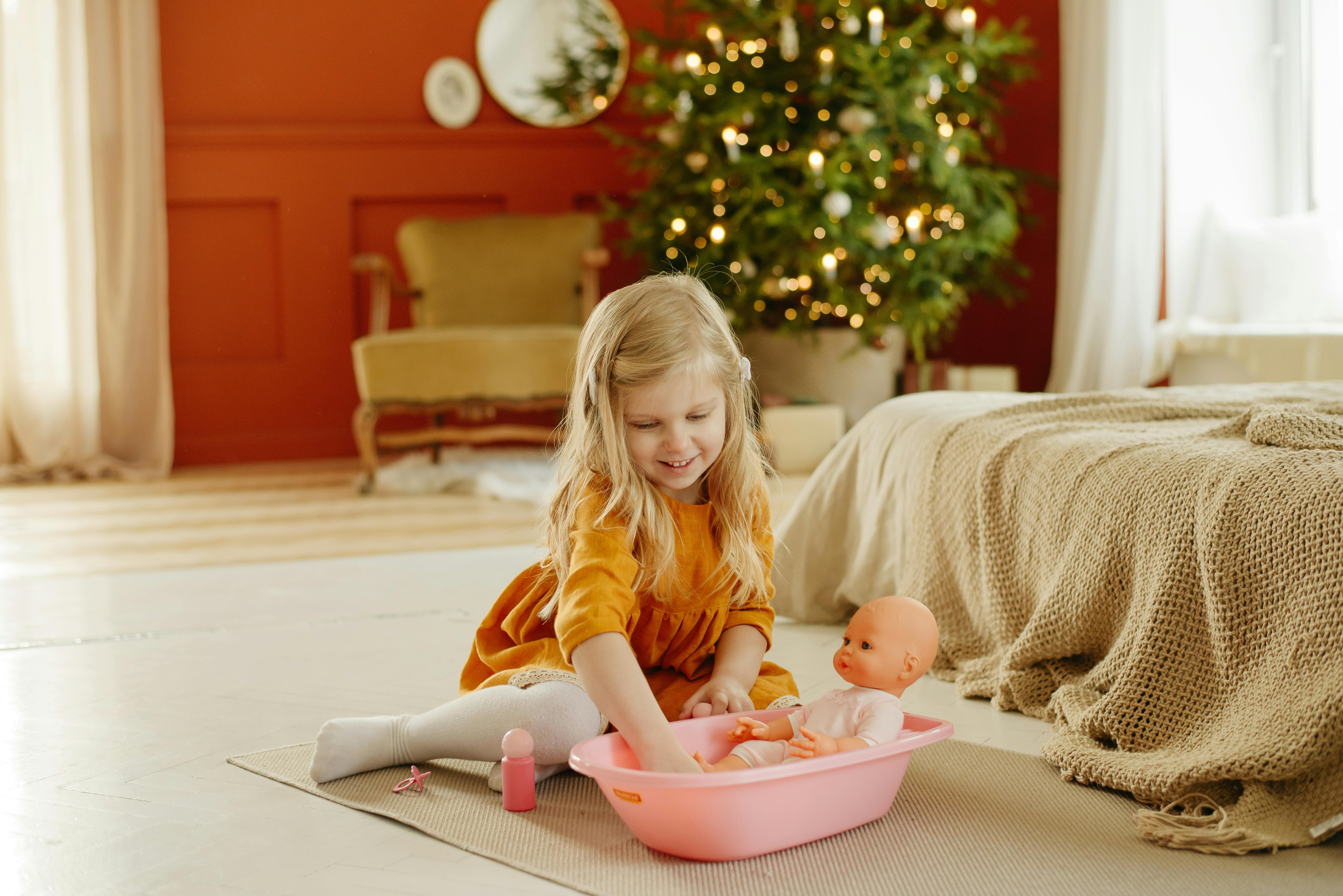 girl in orange dress playing with baby doll