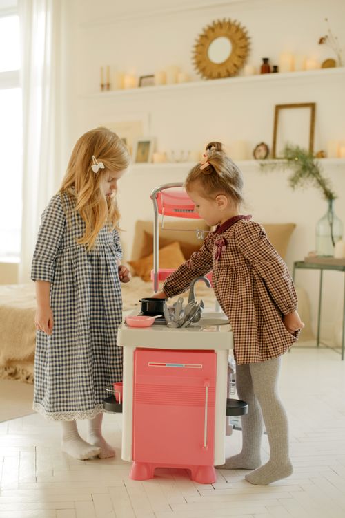 Free Two young girls enjoying playtime with kitchen toys in a cozy indoor setting. Stock Photo