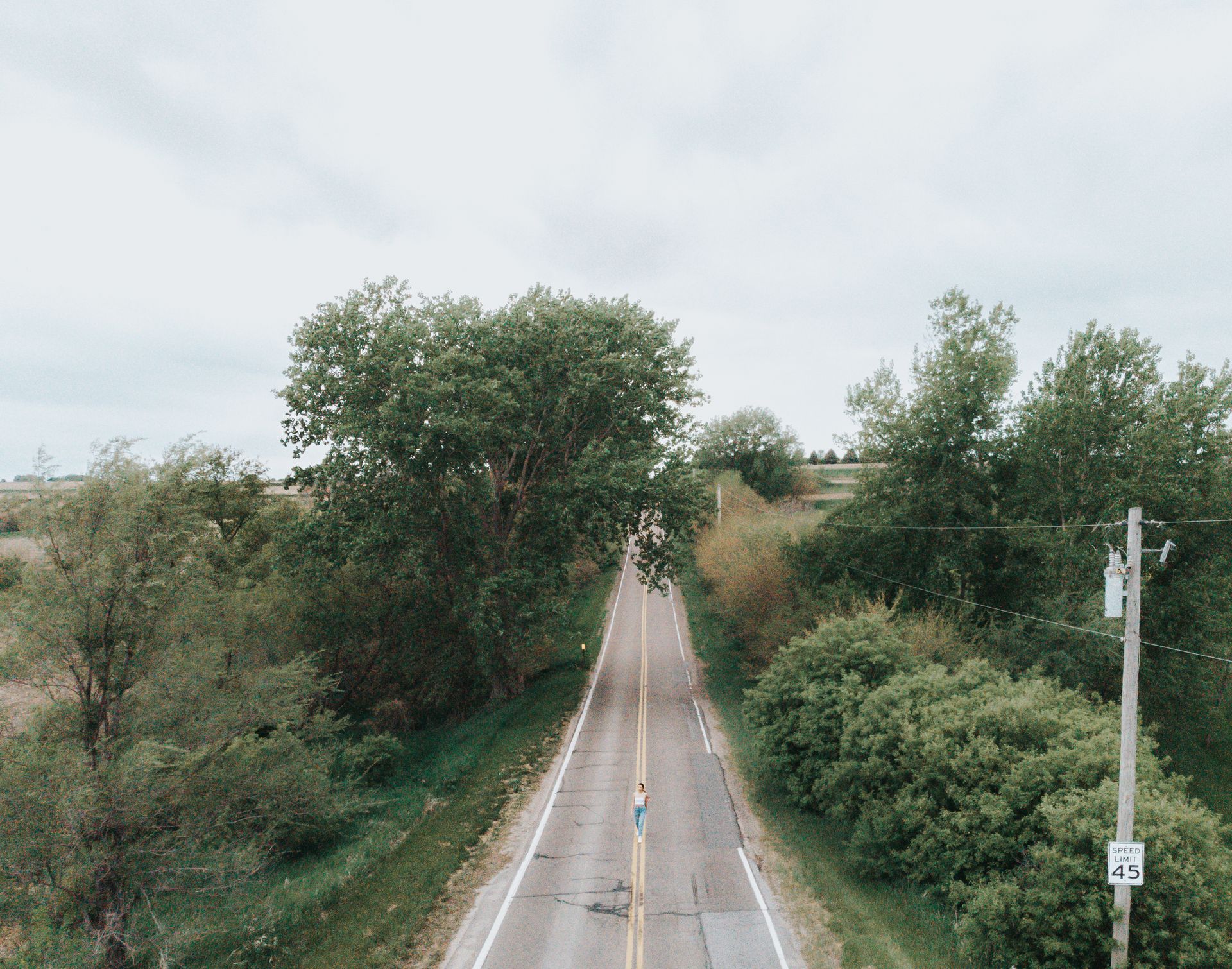 Drone image capturing a woman on a rural road surrounded by lush greenery in Omaha, Nebraska.