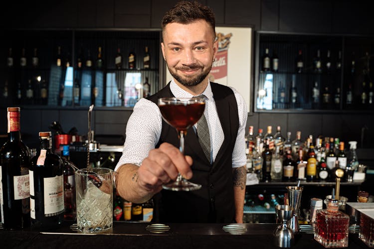 A Man In Black Vest Holding A Glass Of Wine