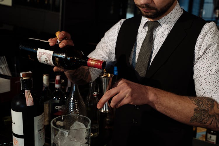 A Man In Black Vest Holding A Wine Bottle