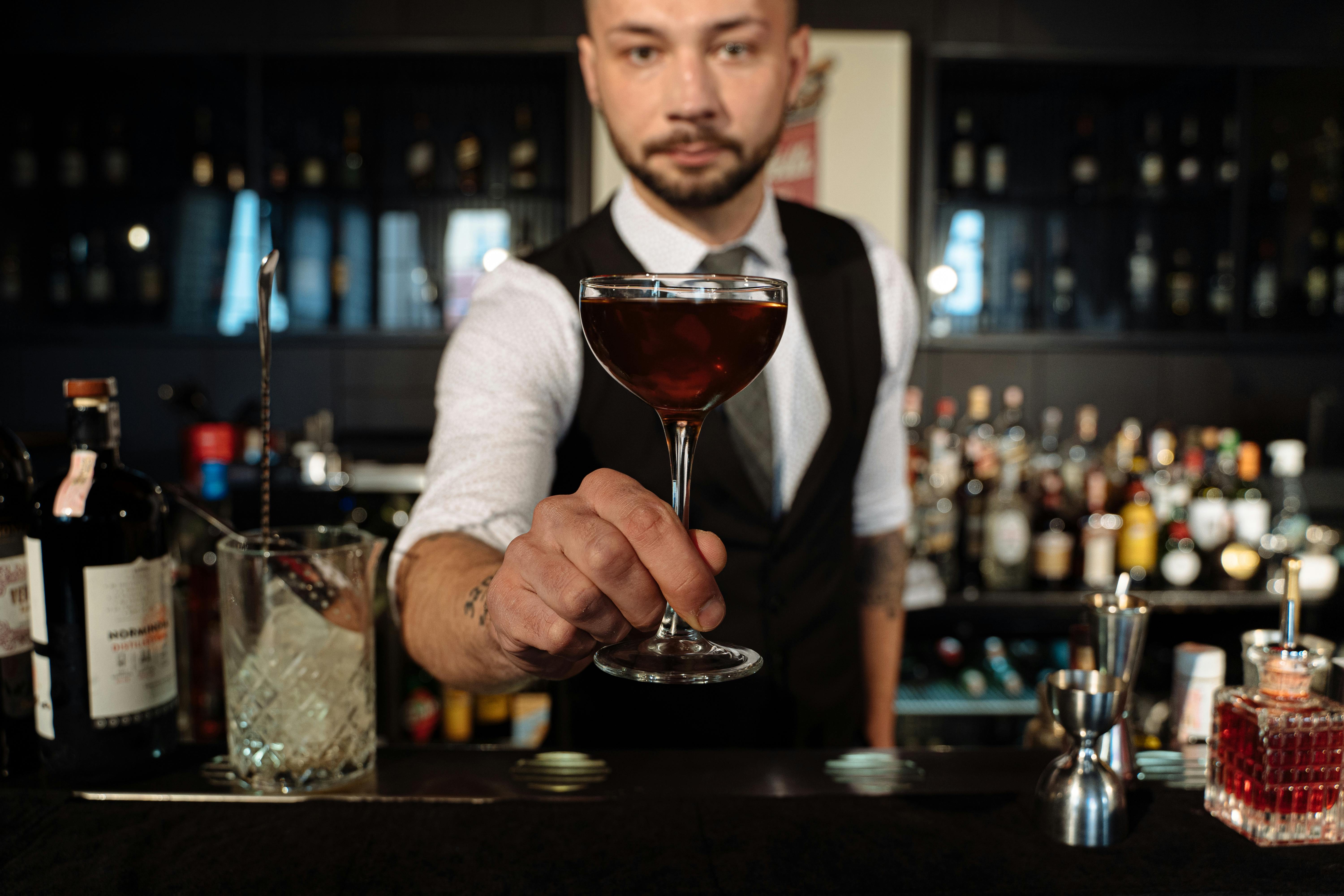 Bartender offering a refined cocktail in a stylish bar setting, perfect for nightlife scenes.