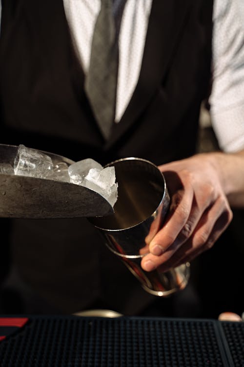 A Person Putting Ice in a Stainless Cocktail Shaker