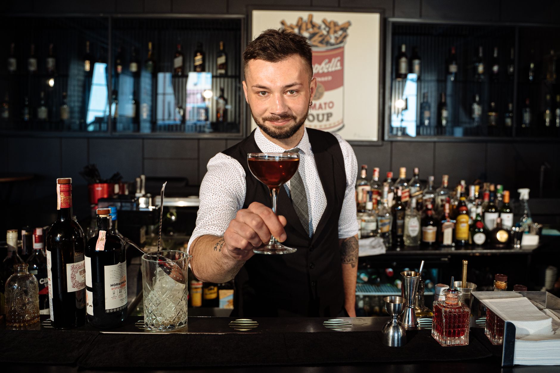 Bartender offers a crafted cocktail in a stylish bar, showcasing skills and inviting atmosphere.