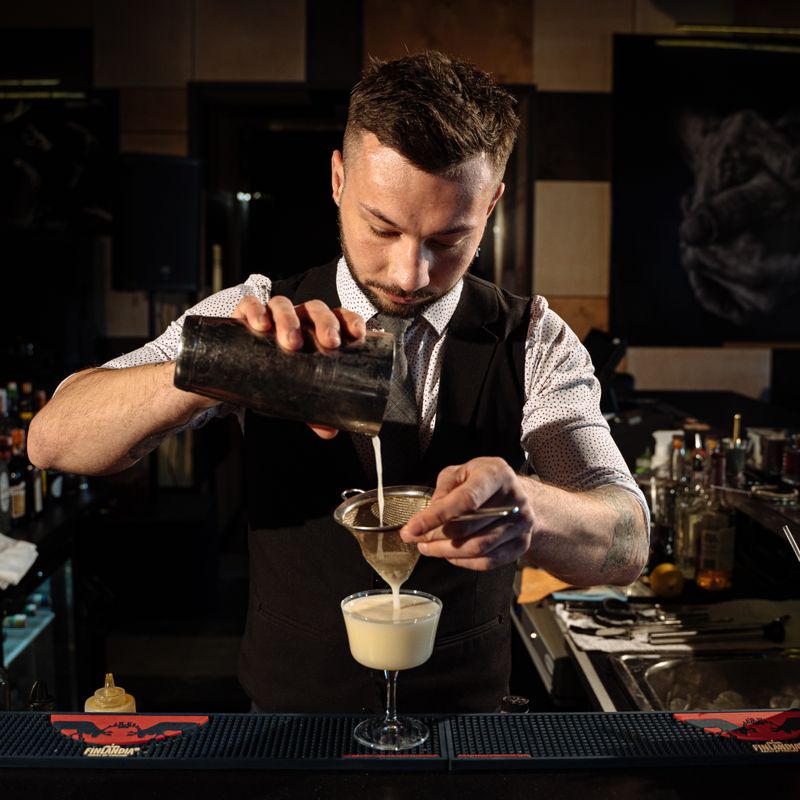 Bartender pouring a cocktail through a strainer