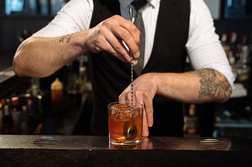 Free A bartender expertly blends a cocktail with ice, showcasing professional skills and style. Stock Photo
