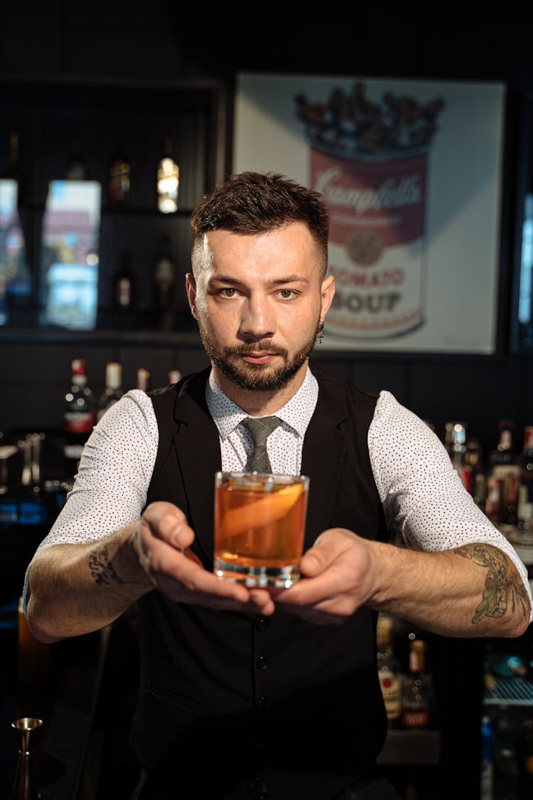 Barman In Black Vest Holding Cocktail In Glass