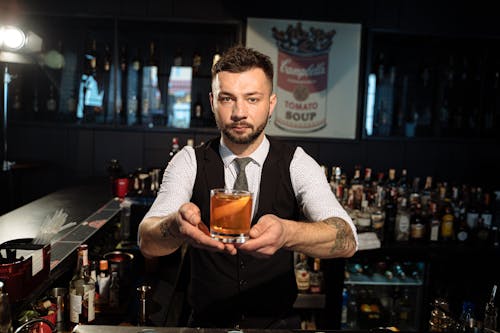 Barman in Black Vest Holding Cocktail in Glass