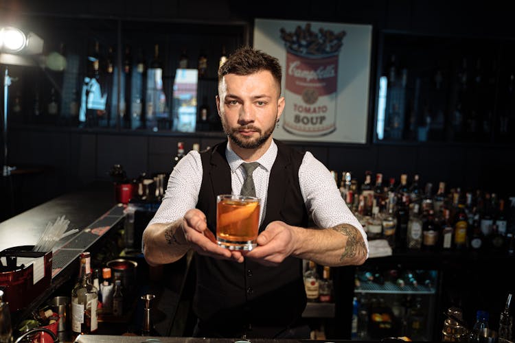 Barman In Black Vest Holding Cocktail In Glass