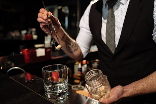 Bartender skillfully crafting a cocktail with precision, using sugar cubes and tongs.