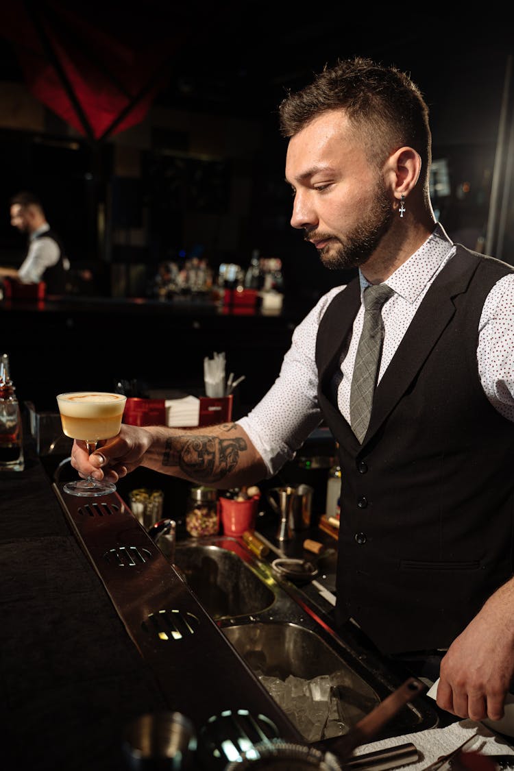 Barman In Black Vest Holding Cocktail In Glass