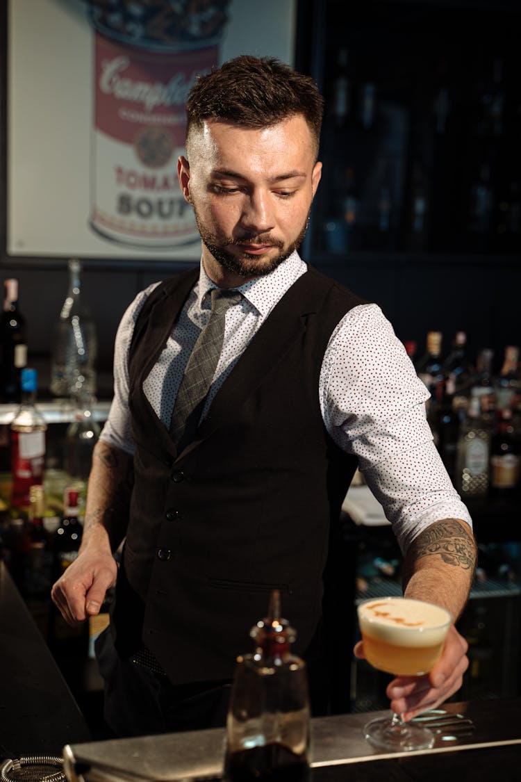 Barman In Black Vest Holding Cocktail In Glass