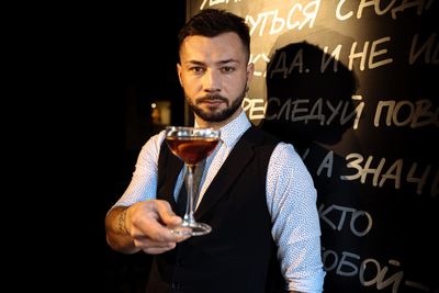 Male bartender presenting a cocktail in a stylish setting