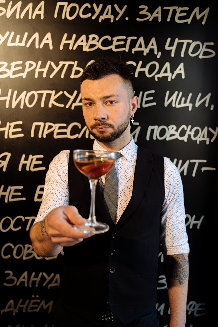 Barman In Black Vest Holding Cocktail In Glass