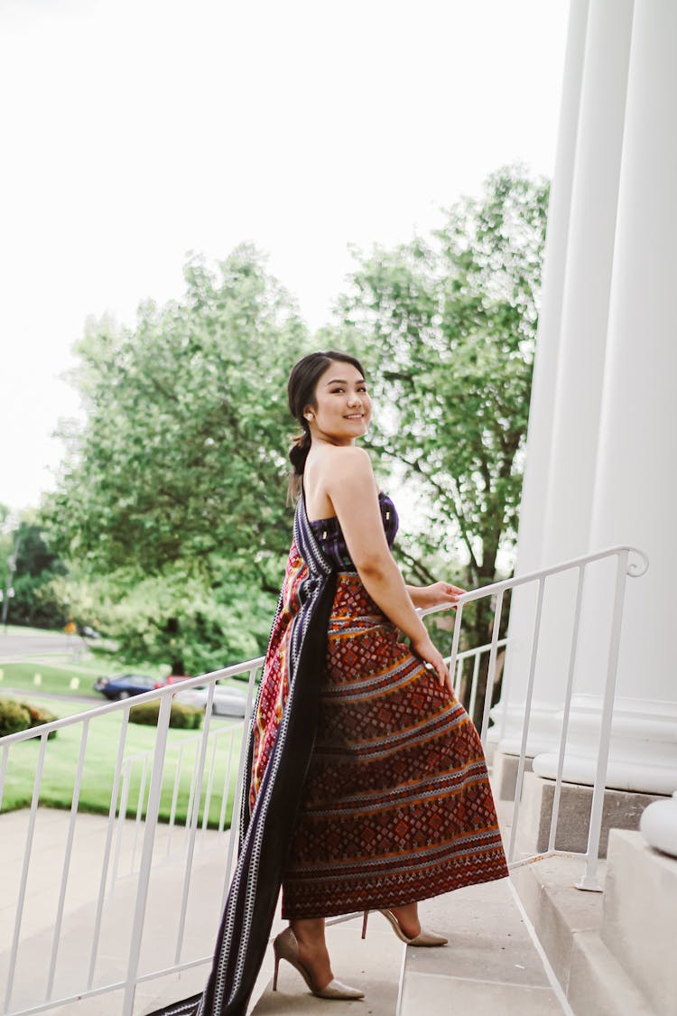 Cheerful Asian Woman In Traditional Dress Ascending Staircase