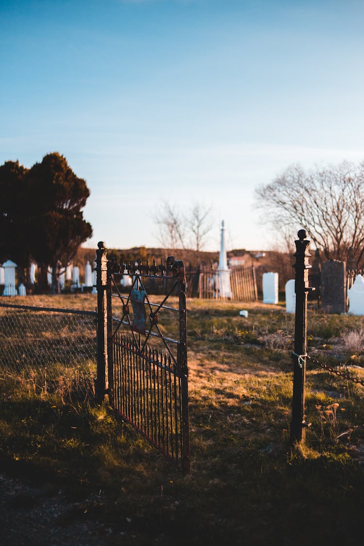 Open Gate To Aged Graveyard Under Sky In Autumn