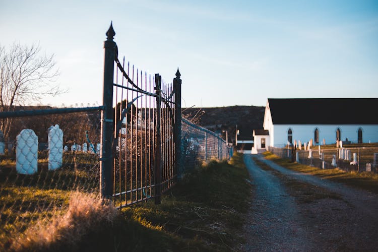 Metal Gate Near Walkway And Aged Building In Cemetery