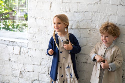 Free Two Children with Blond Hair Standing Beside White Wall Stock Photo