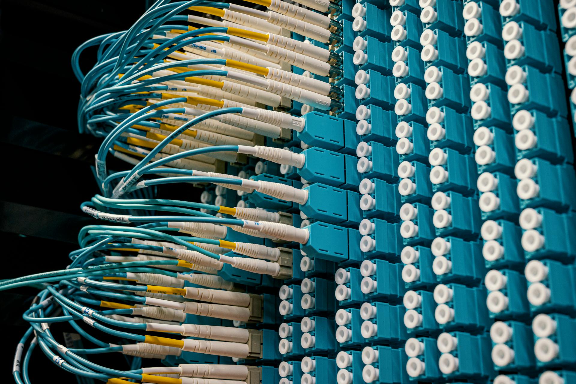 Detailed view of fiber optic patch cables connecting to a blue patch panel in a data center.