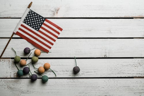 Free Top view of national USA flag near small tropical fruits on wooden surface Stock Photo