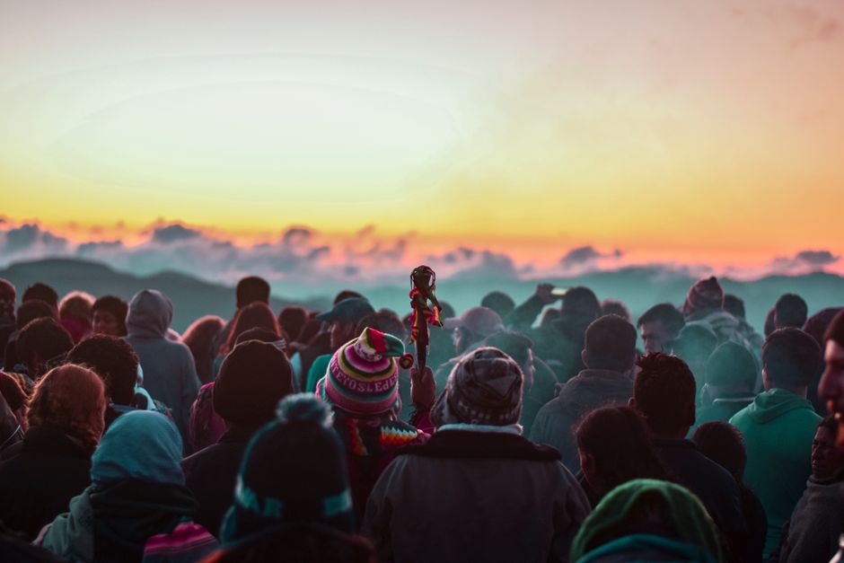A colorful crowd gathers at sunset in Samaipata, Bolivia, against a stunning mountain backdrop.