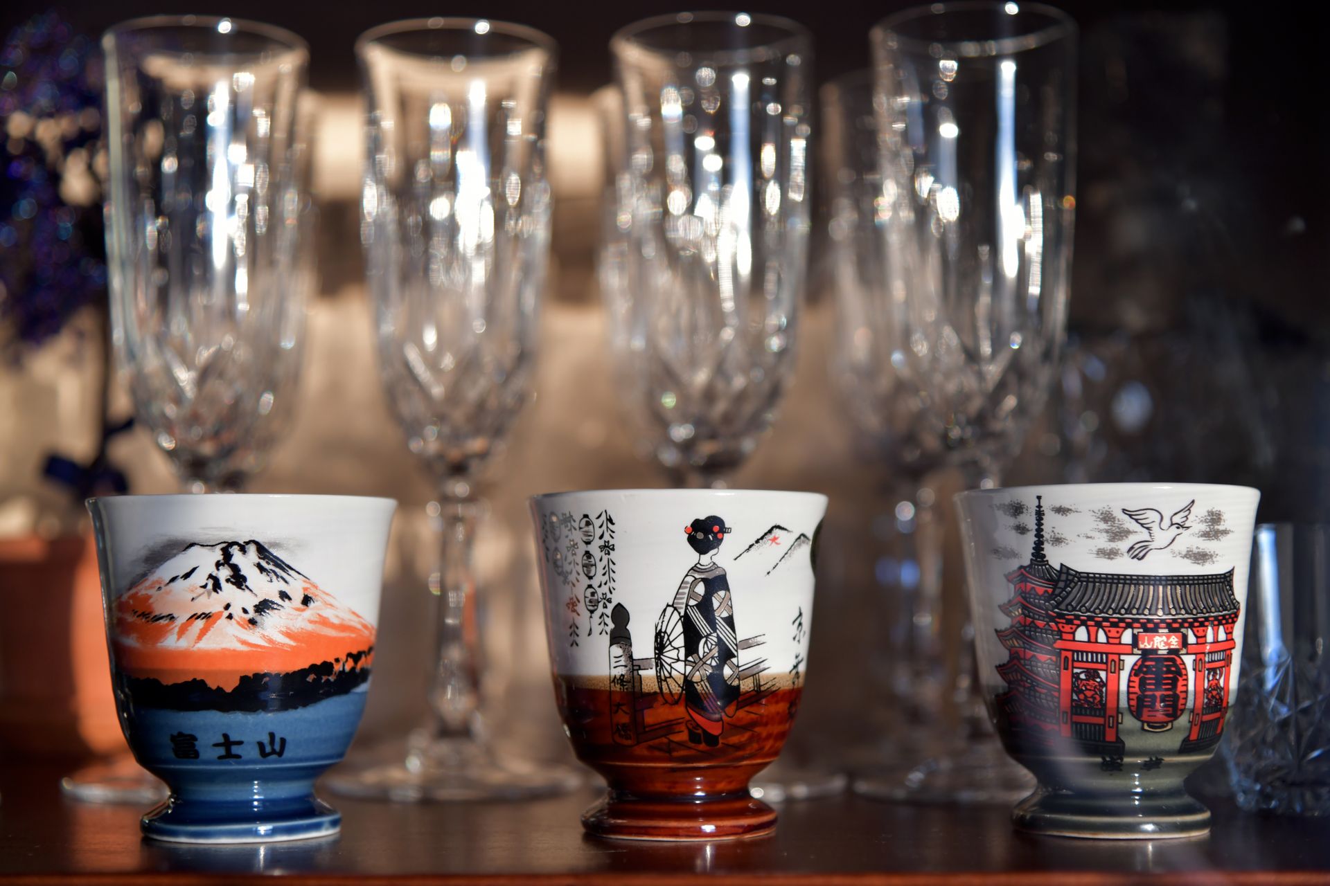 Artistic display of Japanese ceramic teacups and elegant crystal glasses, highlighting traditional designs.