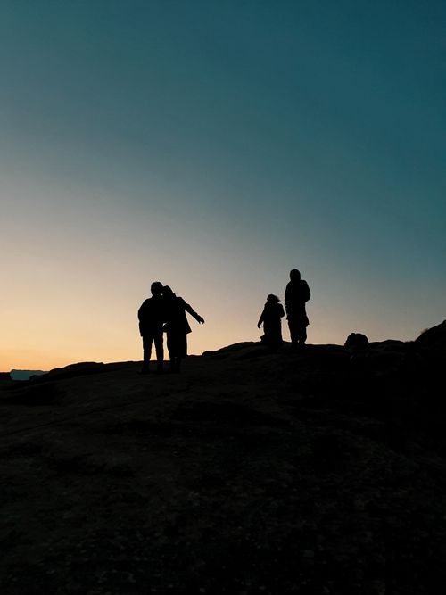 Free Silhouetted figures of a family on a hill at sunset in Georgia, creating a serene rural scene. Stock Photo