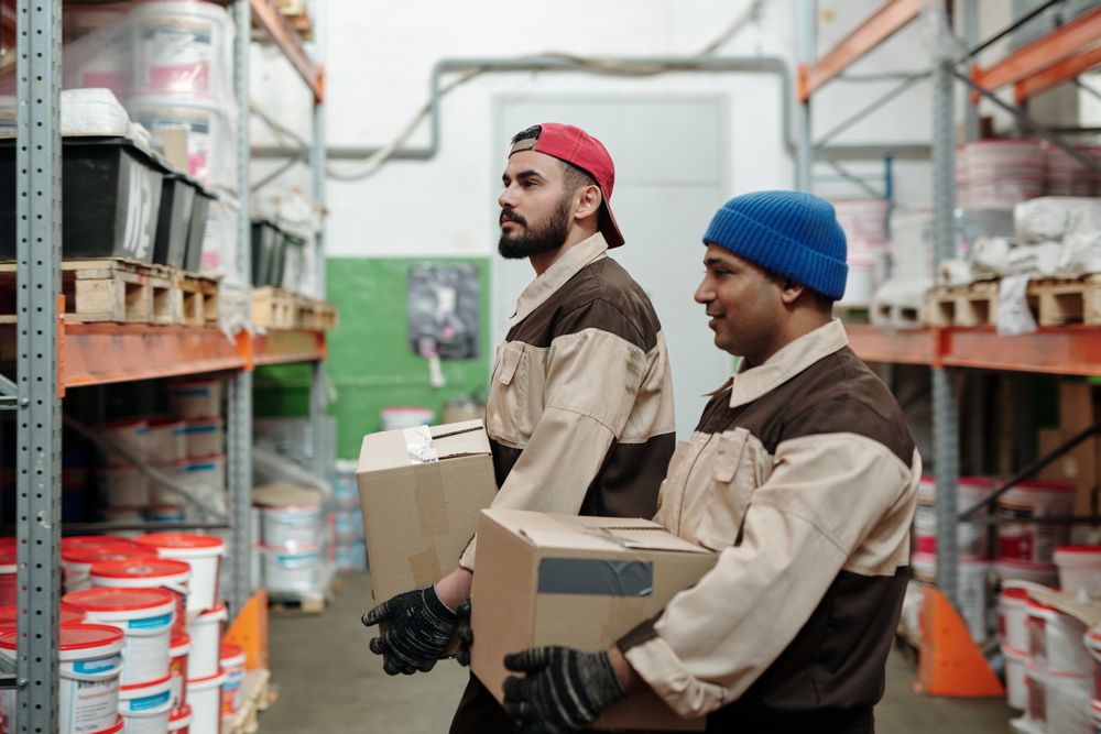 Equipe de salariés en entrepôt logistique manipulant des cartons, illustrant la prévention SST en PME
