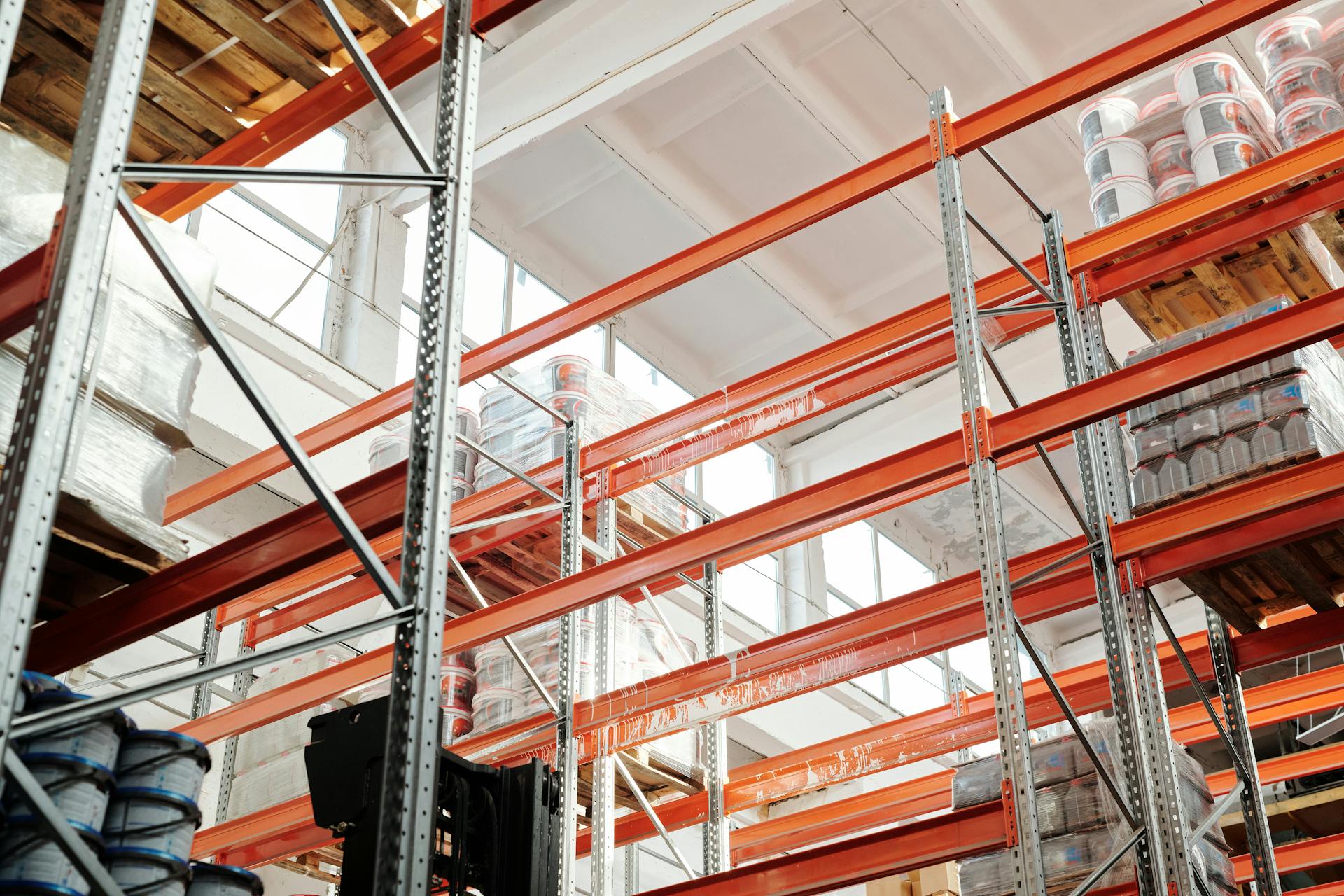 Bright warehouse interior with orange metal shelving units and stored goods.