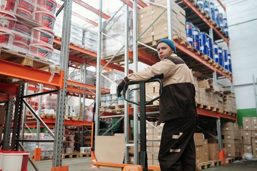 Pallet jack among stacked boxes and metal shelves