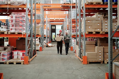 Workers Walking Along Aisle in Warehouse