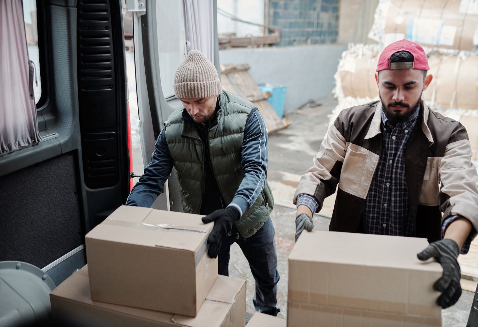 Two movers loading packages into a large delivery van