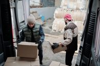 Man in Black Jacket and Brown Knit Cap Holding Brown Cardboard Box