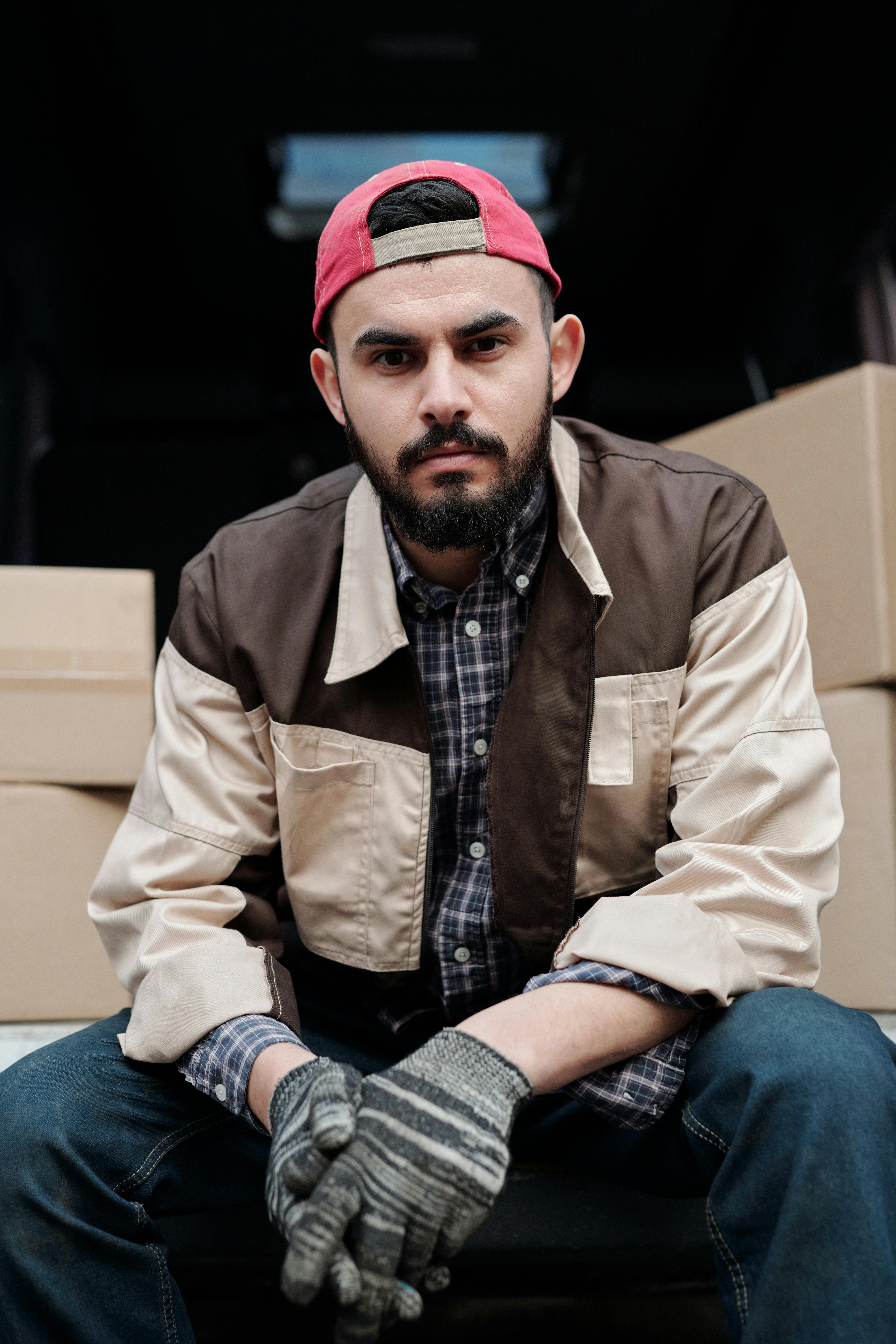 一名送货员穿着休闲工作服，坐在一辆被纸板箱包围的货车里